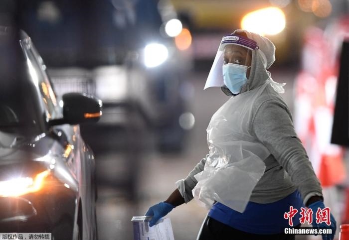 當(dāng)?shù)貢r(shí)間12月18日，英國(guó)政府公布的數(shù)據(jù)顯示，當(dāng)天英國(guó)新增奧密克戎毒株感染病例10059例。鑒于奧密克戎毒株感染病例激增，住院人數(shù)不斷上升，倫敦市長(zhǎng)宣布倫敦進(jìn)入“重大事故”狀態(tài)。圖為倫敦的一個(gè)免下車檢測(cè)中心，一名醫(yī)務(wù)工作者正準(zhǔn)備對(duì)司機(jī)進(jìn)行核酸檢測(cè)。