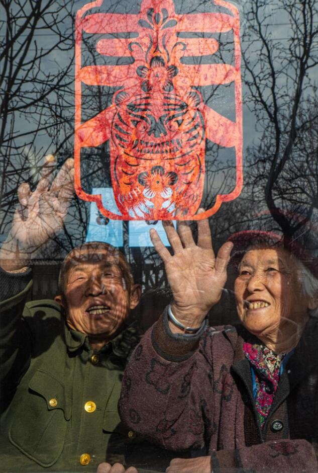 臘月里，霍州市師莊鄉(xiāng)馮南垣村村民師榮光(左)在災(zāi)后重建的新家里貼窗花。(霍州市委宣傳部供圖)