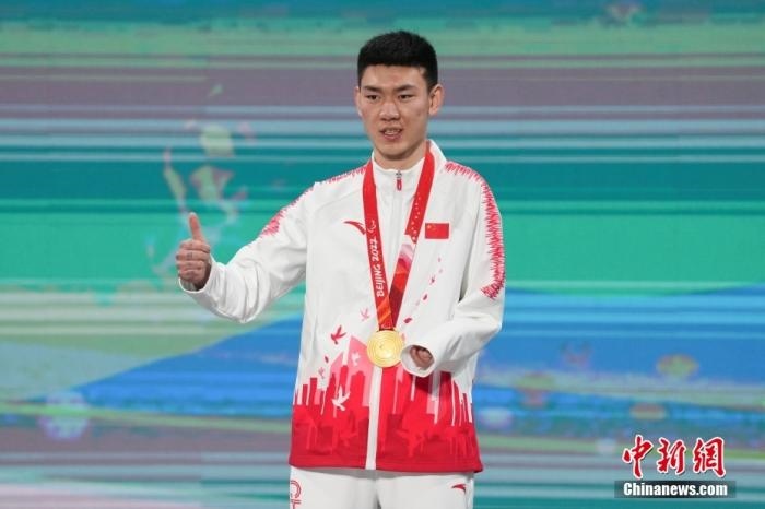 3月6日，梁景怡在延慶頒獎廣場領(lǐng)獎臺上豎起大拇指。當日，在國家高山滑雪中心舉行的北京2022年冬殘奧會殘奧高山滑雪男子超級大回轉(zhuǎn)—站姿決賽中，中國選手梁景怡奪得冠軍。 <a target='_blank' href='/'>中新社</a>記者 楊華峰 攝