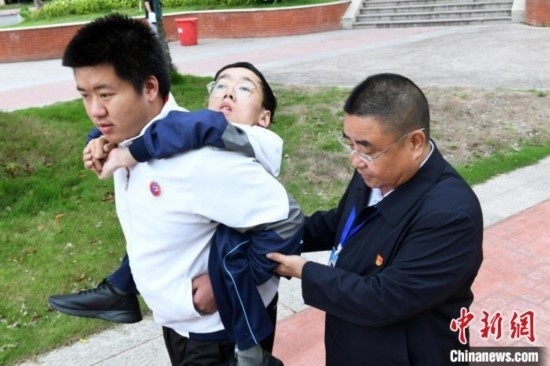 朱金祥背著鐘華強去教室上課的路上，也經(jīng)常碰到值班的校領導和老師前來搭把手。 卓忠偉 攝