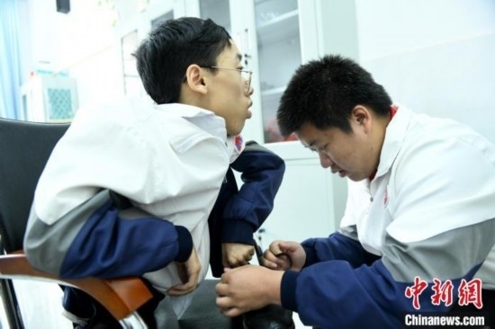 江西省南康中學北校區(qū)的高三學生朱金祥(右)正在給鐘華強(左)系好鞋帶。 卓忠偉 攝