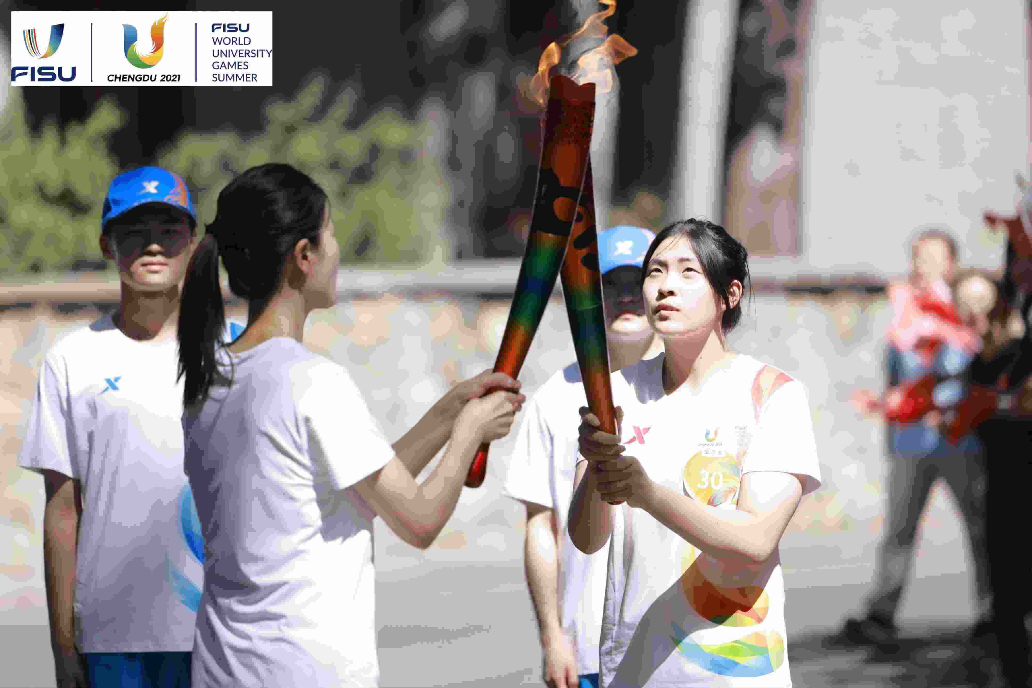 兩名大運(yùn)會(huì)火炬手進(jìn)行火炬?zhèn)鬟f。 圖片來源：成都大運(yùn)會(huì)執(zhí)委會(huì)供圖