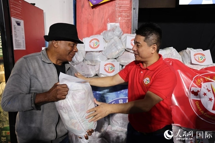 巴西中國浙江商會(huì)會(huì)長(zhǎng)鄭俠茂向社區(qū)居民轉(zhuǎn)交捐贈(zèng)物資。人民網(wǎng)記者 時(shí)元皓攝