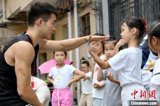 圖為大學(xué)生志愿者在組織孩子們參加體育健身活動(dòng)。廖光福 攝