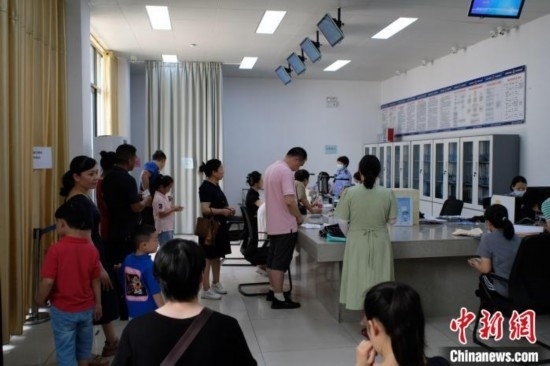 圖為在戶籍辦證廳內(nèi)排隊等待的家長和孩子。劉俊聰 攝