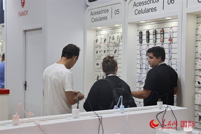 幾名參觀者在一個展臺前了解手機配件。（人民網(wǎng)記者 時元皓攝）