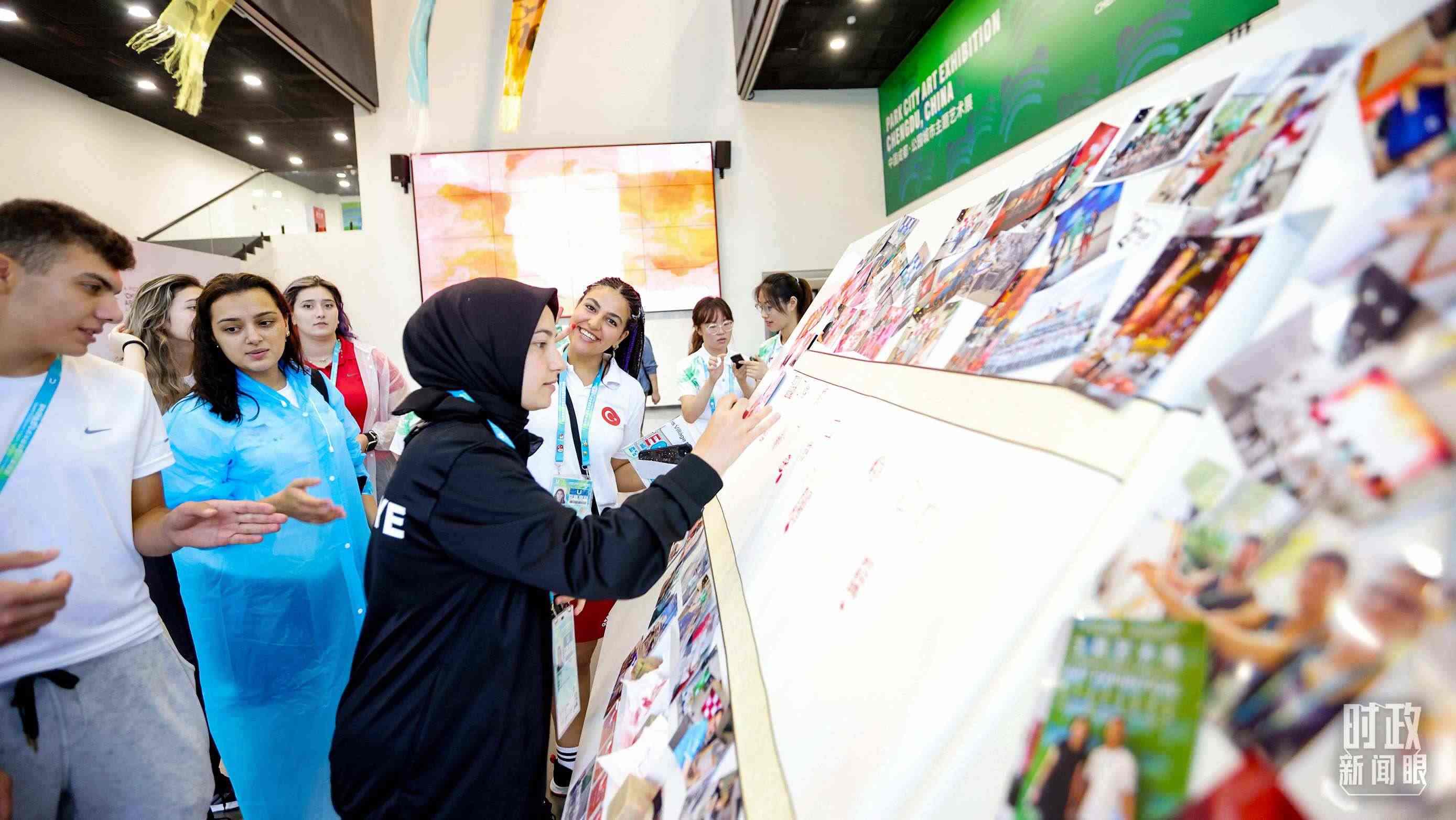 各國(guó)青年運(yùn)動(dòng)員正在參觀成都大運(yùn)村內(nèi)的“雪山下的公園城市，煙火里的幸福成都”主題藝術(shù)展。（總臺(tái)央視記者魏幫軍拍攝）