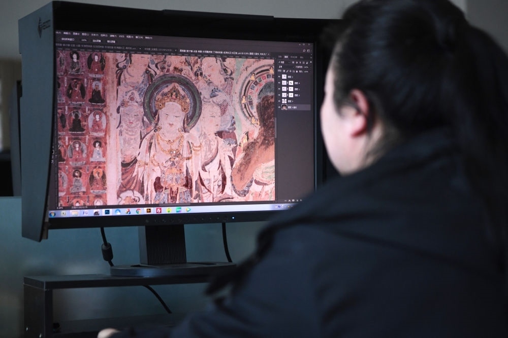 敦煌研究院文物數(shù)字化保護(hù)團(tuán)隊(duì)圖像處理人員年海麗在拼接壁畫圖像（2023年4月25日攝）。數(shù)字化探索為莫高窟的保護(hù)與傳承開辟了全新路徑，數(shù)字技術(shù)讓敦煌文物走出洞窟，跨出國(guó)門，走向“永久保存、永續(xù)利用”。新華社記者 陳斌 攝
