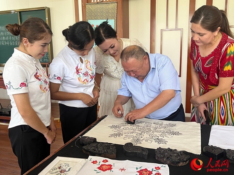 國(guó)家級(jí)非物質(zhì)文化遺產(chǎn)模戳印花布技藝傳承人吾吉阿西木?吾舒爾展示模戳印花布的制作過(guò)程。人民網(wǎng)記者 常雪梅攝