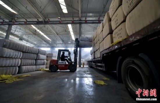 新疆喀什綜合保稅區(qū)，喀什啟路國際貿(mào)易有限公司的倉庫內(nèi)，工人正在裝載從塔吉克斯坦和烏茲別克斯坦進(jìn)口的棉花。劉新攝