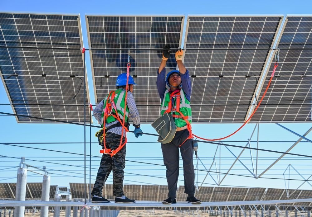 2023年7月22日，工人在位于內(nèi)蒙古杭錦旗庫布其沙漠億利生態(tài)示范區(qū)的蒙西基地庫布其200萬千瓦光伏治沙項目工地安裝光伏板。新華社記者 劉磊 攝
