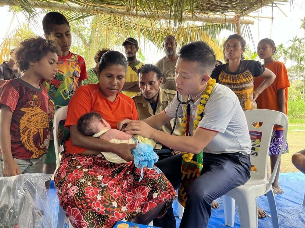 2023年8月5日，在巴布亞新幾內(nèi)亞中央省的一個(gè)村莊里，第12批援巴新中國醫(yī)療隊(duì)副隊(duì)長、新生兒科副主任醫(yī)師劉振球?yàn)楫?dāng)?shù)貗雰郝犜\檢查。新華社發(fā)（第12批援巴新中國醫(yī)療隊(duì)供圖）
