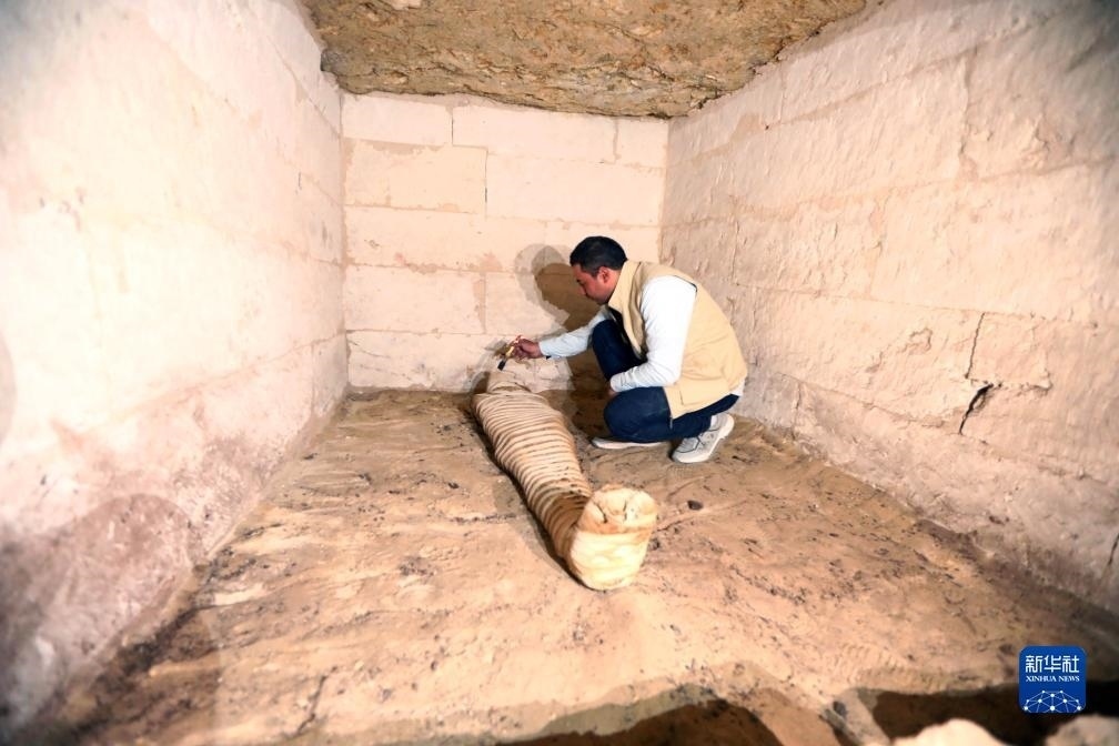 10月15日，在埃及明亞省考古現(xiàn)場(chǎng)，考古人員清理一座石鑿墓中的木乃伊。新華社發(fā)（艾哈邁德·戈馬攝）