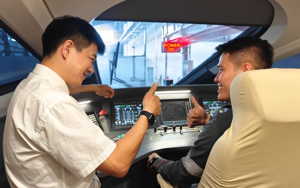 8月25日，在印度尼西亞萬隆的雅萬高鐵德卡魯爾動(dòng)車所內(nèi)，中國師傅穆振（左）在向印尼火車司機(jī)塞蒂亞萬講解動(dòng)車組出庫前的上電作業(yè)。