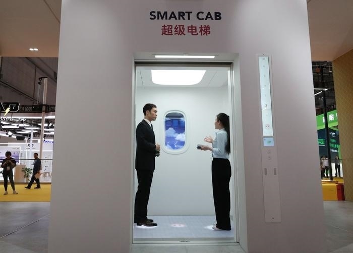 11月5日，工作人員（右）在第六屆進(jìn)博會(huì)上向參觀者介紹奧的斯公司全新推出的超級電梯。