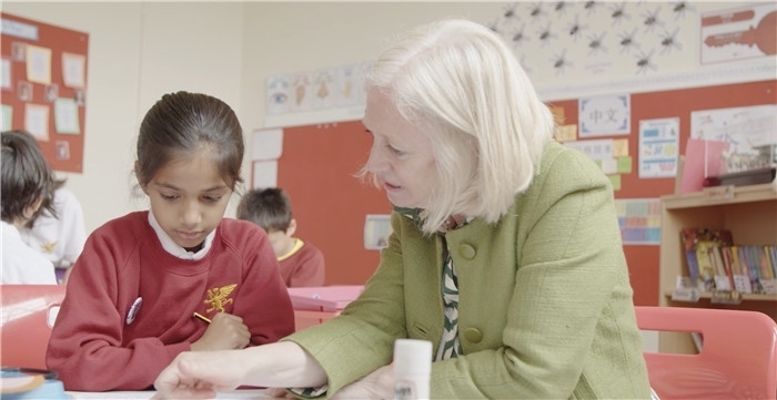 圖為喬·華萊士在教室輔導(dǎo)學生學習