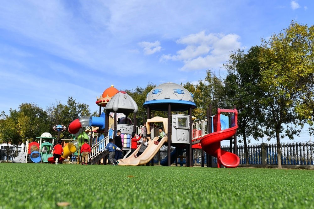 在山東省東營市墾利區(qū)楊廟社區(qū)幼兒園，孩子們?cè)诶蠋煹膸ьI(lǐng)下進(jìn)行戶外活動(dòng)（2021年10月19日攝）。新華社記者 郭緒雷 攝