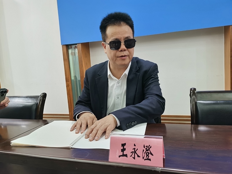 全國人大代表王永澄正在閱讀盲文版代表建議答復(fù)。本報記者 張 璁?dāng)z