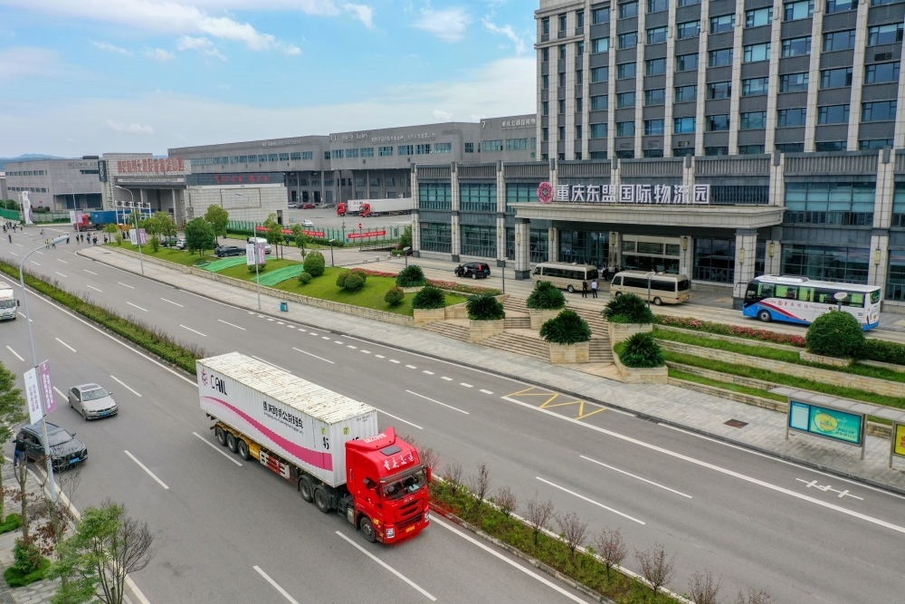 2023年10月11日，滿(mǎn)載筆記本電腦配件、發(fā)電機(jī)組件等產(chǎn)品的西部陸海新通道跨境公路班車(chē)從重慶南彭公路保稅物流中心駛出，將途經(jīng)廣西憑祥，直達(dá)越南（無(wú)人機(jī)照片）。新華社記者 黃偉 攝