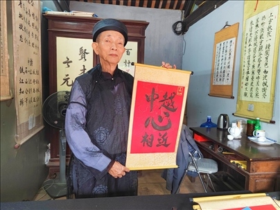 越南首都河內(nèi)文廟內(nèi)，阮明珠展示“中越心相近”書法作品。