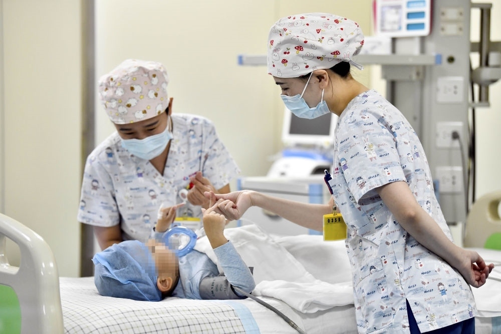 在山東省棗莊市婦幼保健院兒童ICU病房，醫(yī)護人員為完成靶向治療藥物諾西那生鈉的4歲脊髓性肌萎縮癥患兒加油鼓勁（2022年1月1日攝）。諾西那生鈉注射液是我國首個獲批治療脊髓性肌萎縮癥的進口藥物，2019年進入中國市場時，每針價格近70萬元。在2021年國家醫(yī)保目錄藥品談判中，以3.3萬元每針的價格進入新版醫(yī)保藥品目錄。新華社記者 郭緒雷 攝