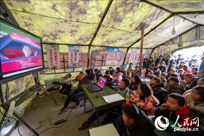 12月22日，在積石山縣大河家鎮(zhèn)大河村安置點，陸軍76集團軍某旅搭建的“臨時學(xué)?！眱?nèi)，小朋友正在看動畫片。人民網(wǎng)記者 翁奇羽攝