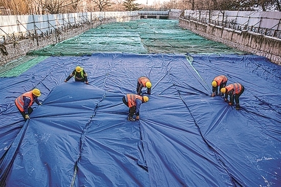 1月3日，房山區(qū)東風街道，工人正在修復的河道內給混凝土鋪設保溫布。