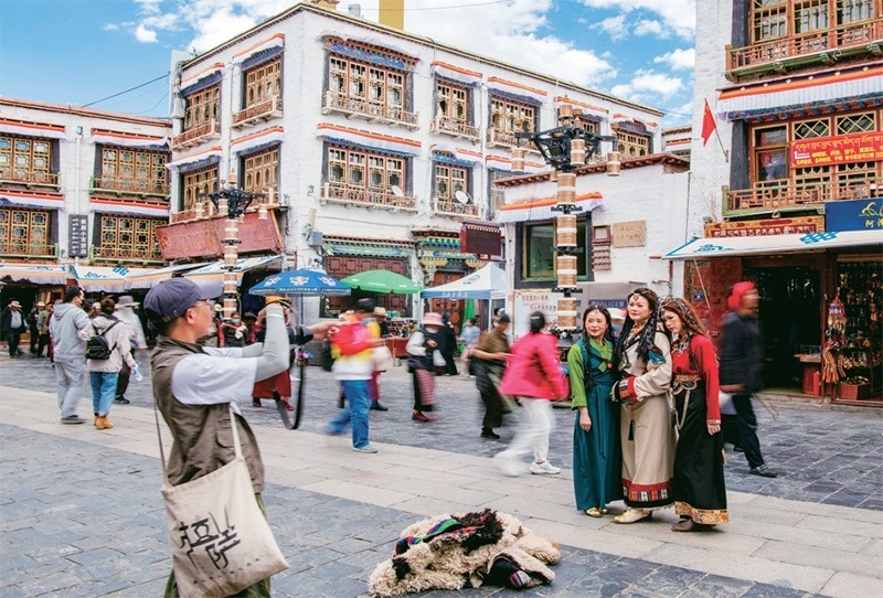 千年八廓街，見證民族團結。2021年7月，習近平總書記來到位于西藏拉薩老城區(qū)的八廓街，感慨地說：“千年八廓街，是我們各民族建起來的八廓街。各民族文化在這里交流交往交融，我們中華民族的大家庭在這里其樂融融?！眻D為2023年6月13日，游客身著藏裝在八廓街拍照留念。 新華社記者 姜帆/攝