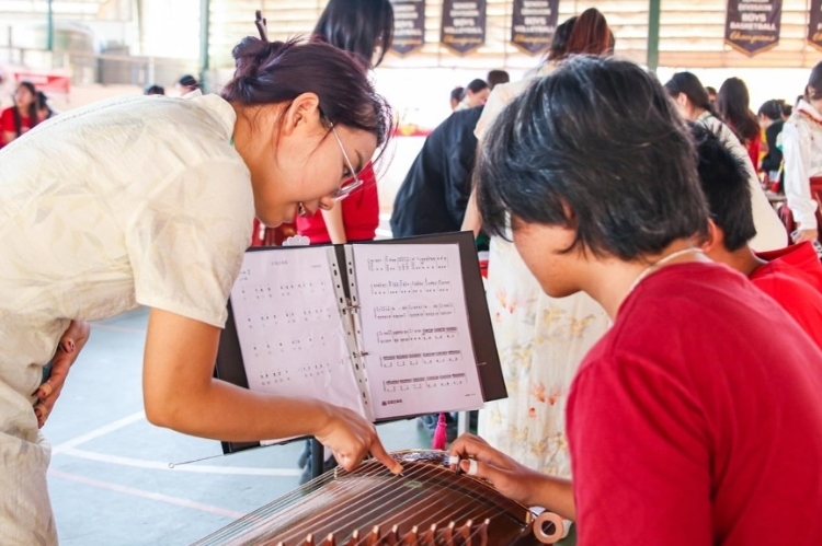 志愿者教師指導(dǎo)學(xué)生彈奏古箏。活動(dòng)主辦方供圖