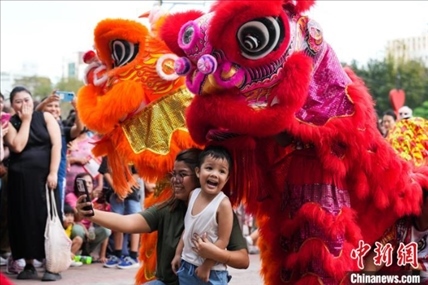 圖為舞獅表演吸引民眾合影。張興龍攝