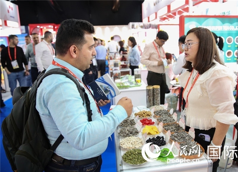 圖為一家中國干果參展企業(yè)代表與采購商洽談。人民網(wǎng) 塔里克·易卜拉欣攝