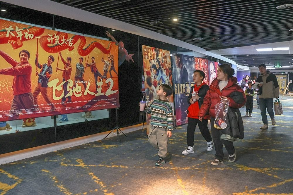 △ 2024年2月16日，在江西贛州一家電影院，觀眾從春節(jié)檔電影的宣傳展板前走過。