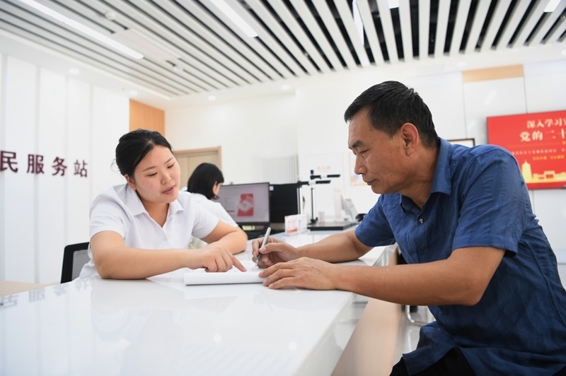 2023年5月23日，河北雄安新區(qū)容東片區(qū)南文營(yíng)社區(qū)居民（右）在社區(qū)便民服務(wù)站辦理業(yè)務(wù)。