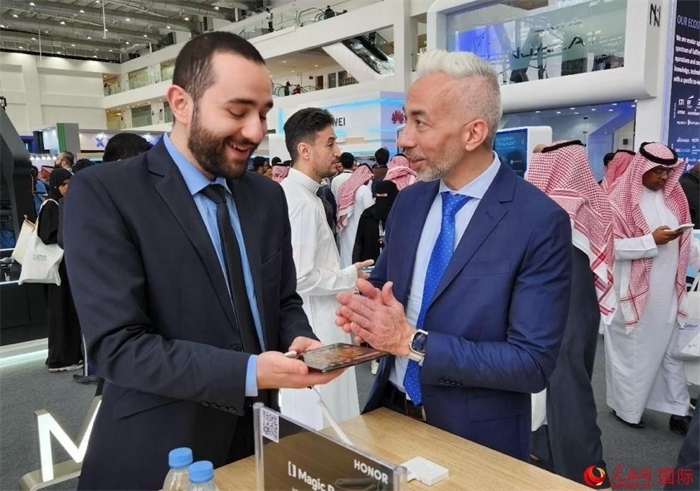 兩名觀眾在榮耀手機(jī)展臺前交流。人民網(wǎng)記者 管克江攝