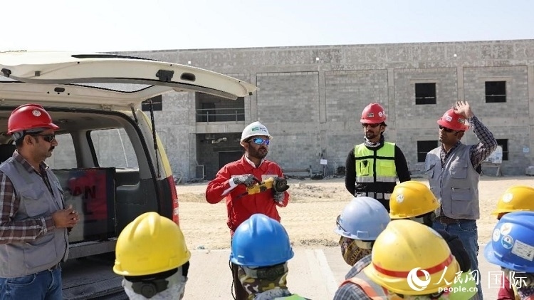 穆薩瓦爾(圖中紅衣人）現(xiàn)場演示工具操作規(guī)范。人民網(wǎng)記者 管克江攝