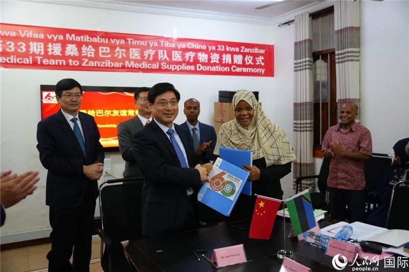 江蘇省蘇北人民醫(yī)院黨委書記束余聲與桑衛(wèi)生部首席秘書哈比巴交換捐贈書。中國援桑醫(yī)療隊供圖