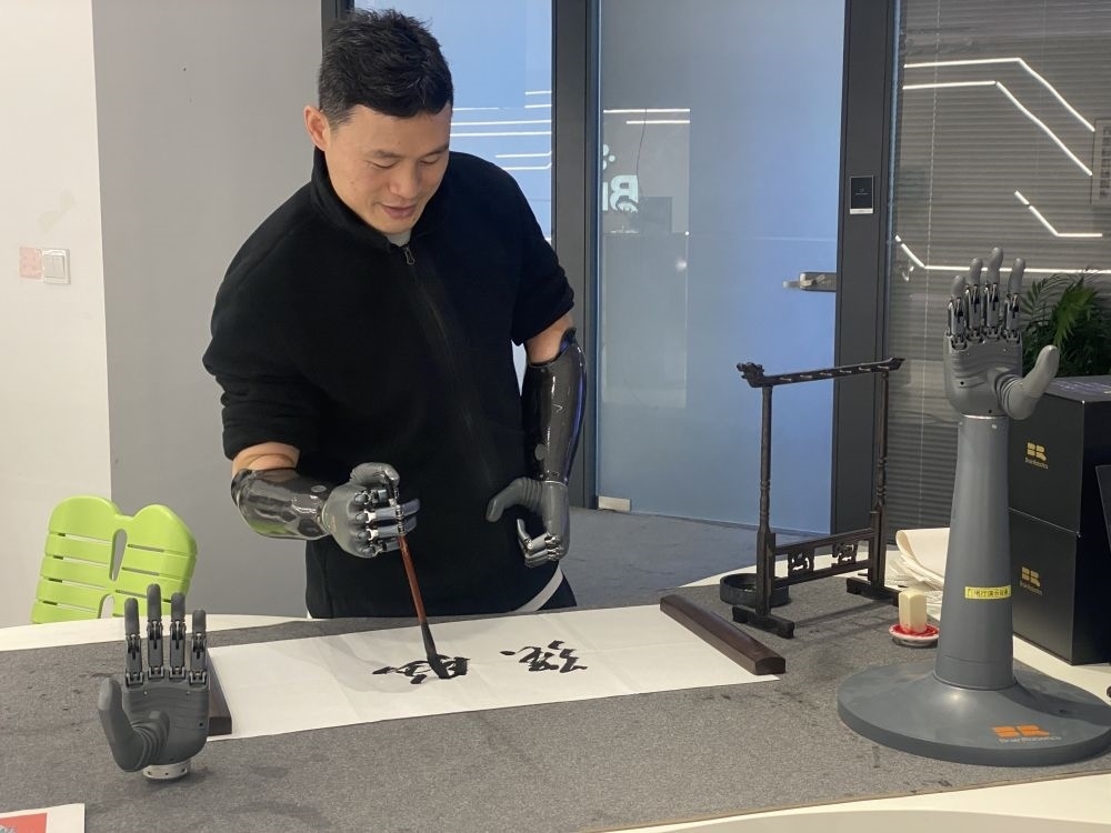 2024年3月29日，在浙江強(qiáng)腦科技有限公司展廳內(nèi)，失去雙手的產(chǎn)品體驗官倪敏成依靠智能仿生手寫毛筆字。新華社記者 魏一駿 攝