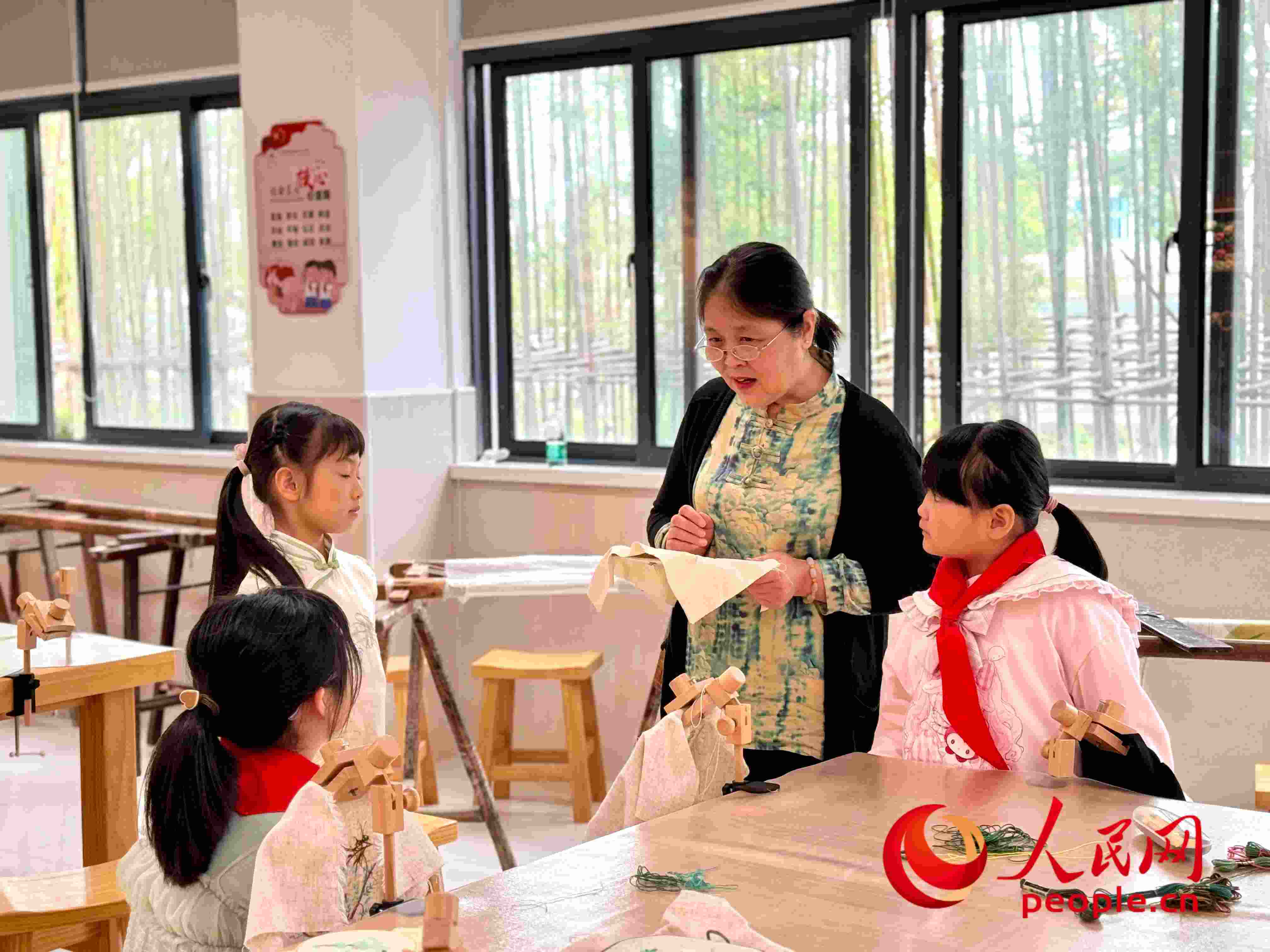 顧建珍（左三）在教孩子們刺繡知識。人民網(wǎng) 周靜圓攝
