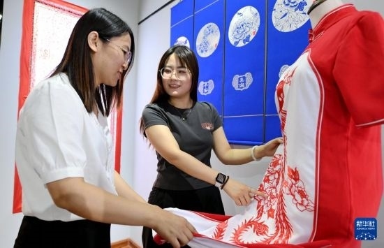 5月31日，在衡水市阜城縣一家剪紙工作室，游客在觀賞帶有剪紙?jiān)氐钠炫邸? width=