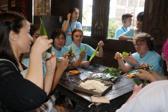 6月9日，美國青年代表在重慶永川松溉古鎮(zhèn)體驗包粽子。新華社記者 周思宇 攝