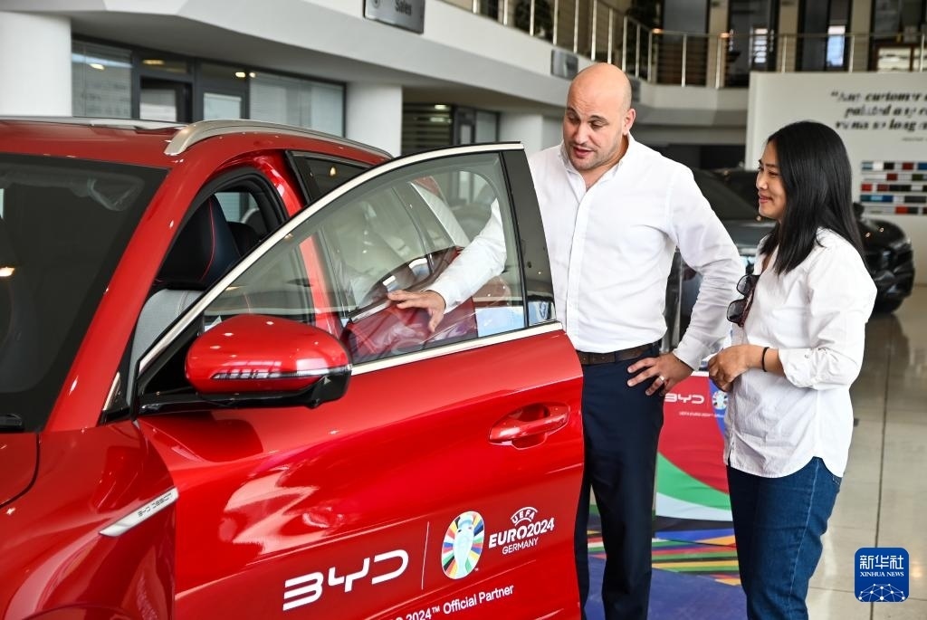 2024年5月29日，在馬耳他比爾基卡拉，馬耳他哈桑-扎米特汽車公司首席執(zhí)行官德古阿拉（左）介紹一輛比亞迪純電動汽車。新華社發(fā)（喬納森·博格 攝）