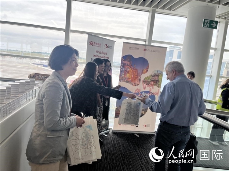 圖為工作人員向乘客發(fā)放復(fù)航首班禮物。 牛瑞飛攝