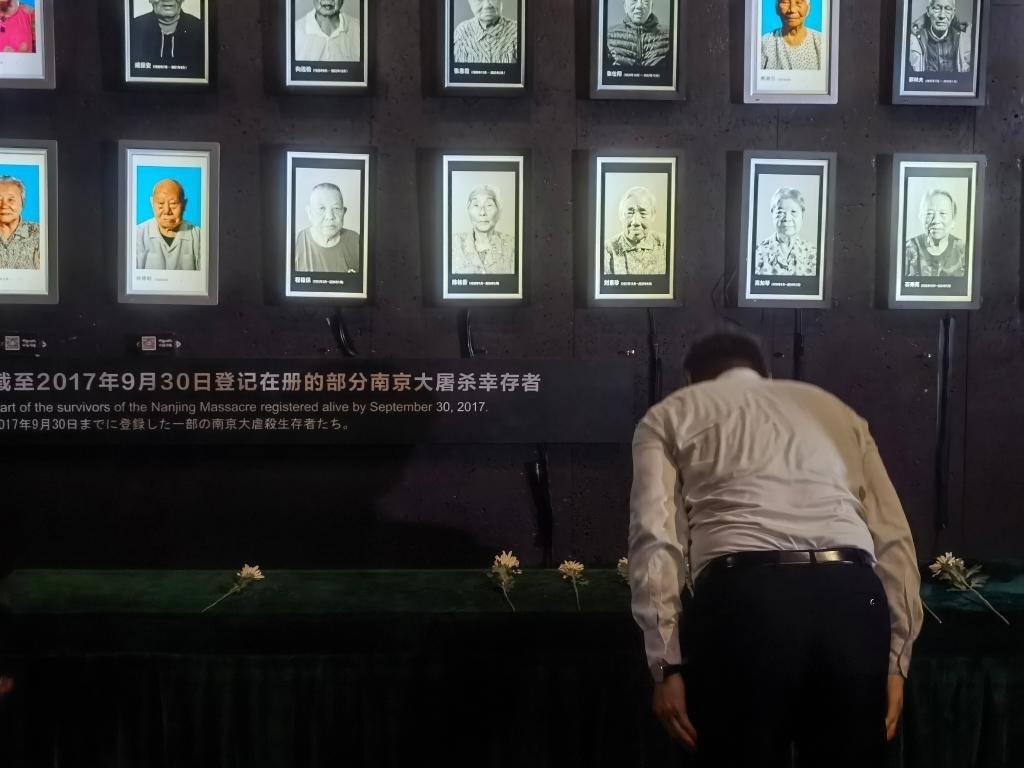 7月18日，人們向離世的南京大屠殺幸存者獻(xiàn)花、鞠躬。新華社記者邱冰清 攝