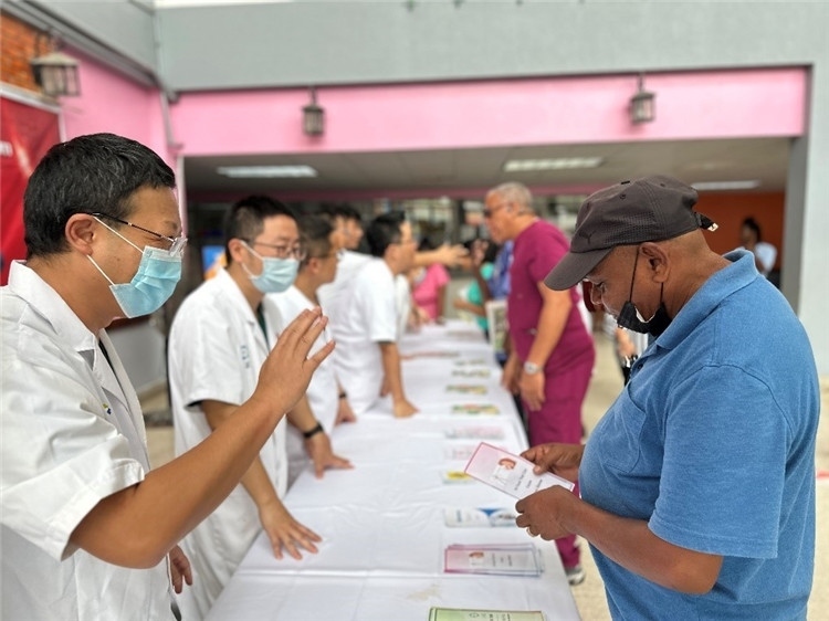 援圭醫(yī)療隊隊員們在啟動儀式上為當?shù)孛癖姺职l(fā)宣傳手冊。中國援助圭亞那醫(yī)療隊供圖