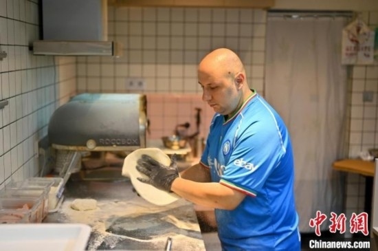 近日，韋榮耀在自家披薩小店內忙活。俞靖 攝