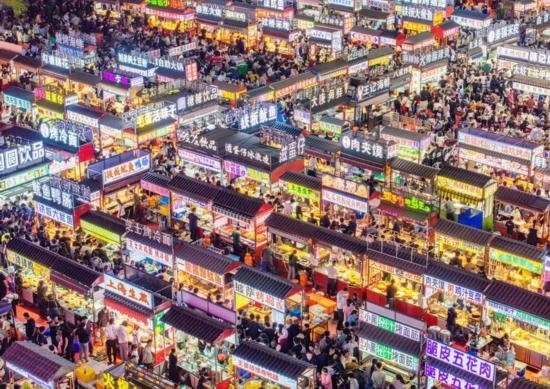 2024年4月21日，人們?cè)诤颖笔≌h小商品夜市品嘗美食（無(wú)人機(jī)照片）。新華社發(fā)（武志偉 攝）