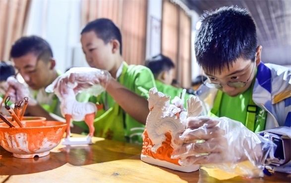 小朋友們在洛陽市孟津區(qū)朝陽鎮(zhèn)南石山村體驗唐三彩素胎施釉技藝。圖片來源：視覺中國