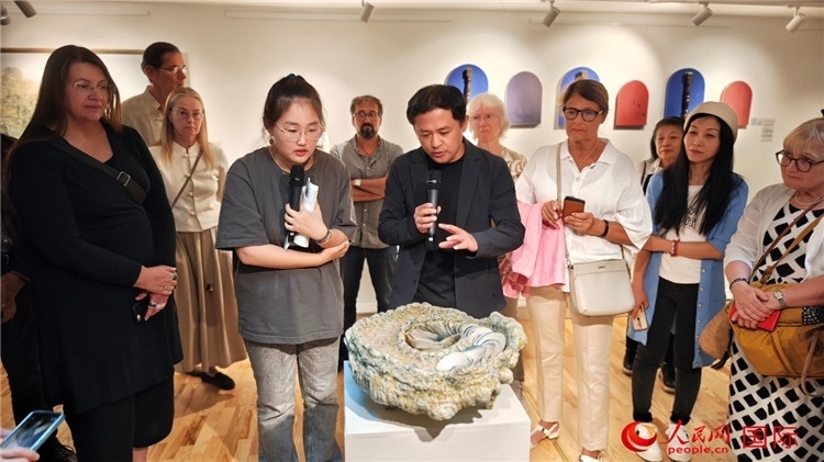 參展人、景德鎮(zhèn)陶瓷大學設(shè)計藝術(shù)學院副院長余劍峰（中）向來賓介紹參展作品。人民網(wǎng)記者 殷淼攝