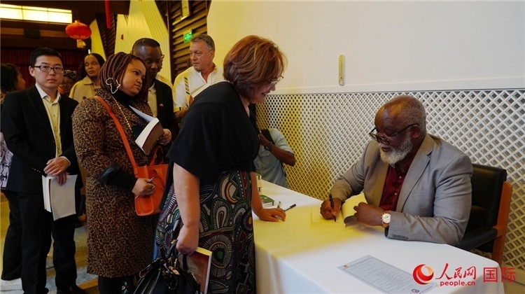 譚哲理在活動現(xiàn)場簽名贈書。人民網(wǎng) 劉暢攝