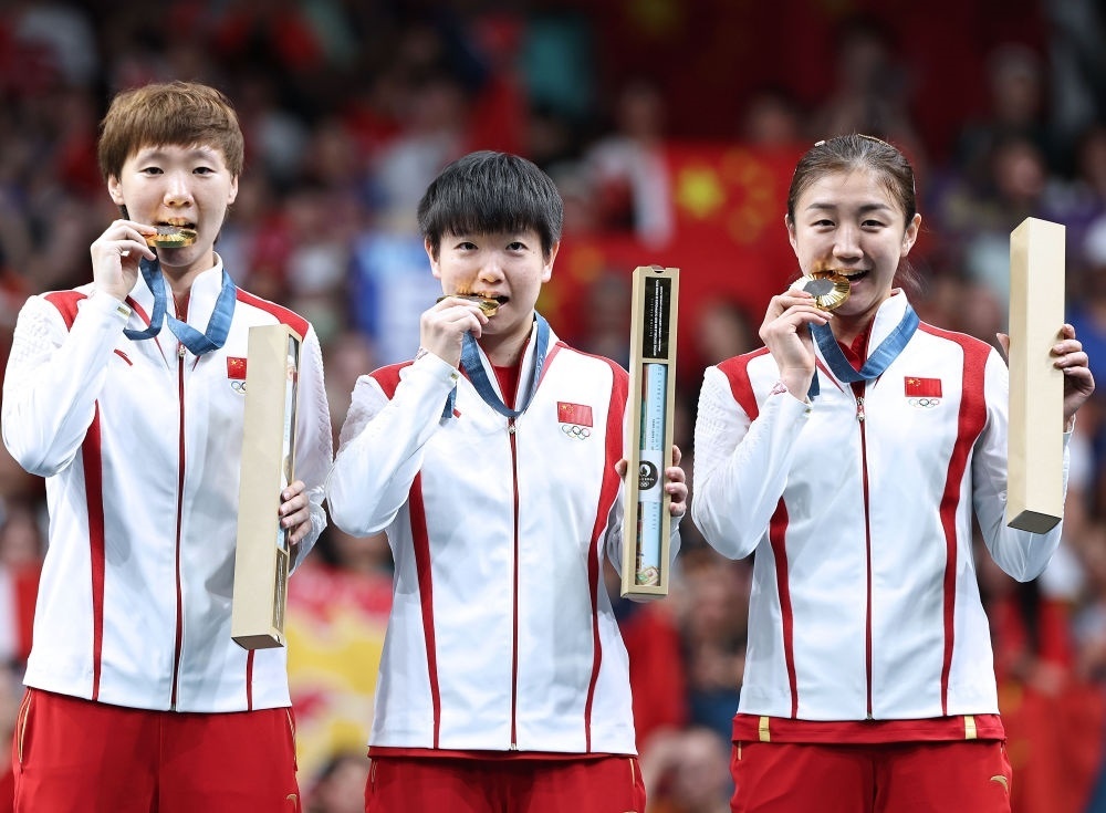 冠軍中國隊選手王曼昱、孫穎莎、陳夢（從左至右）在巴黎奧運(yùn)會乒乓球女子團(tuán)體頒獎儀式上（2024年8月10日攝）。新華社記者 王東震 攝